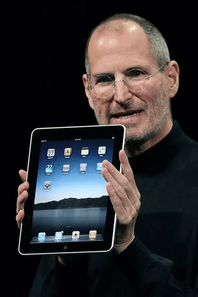 A person presenting a tablet device, displaying its screen with various app icons, during a product launch event.