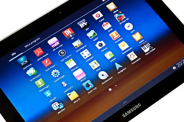 A Samsung tablet displaying a colorful application menu with various icons on a blue background.