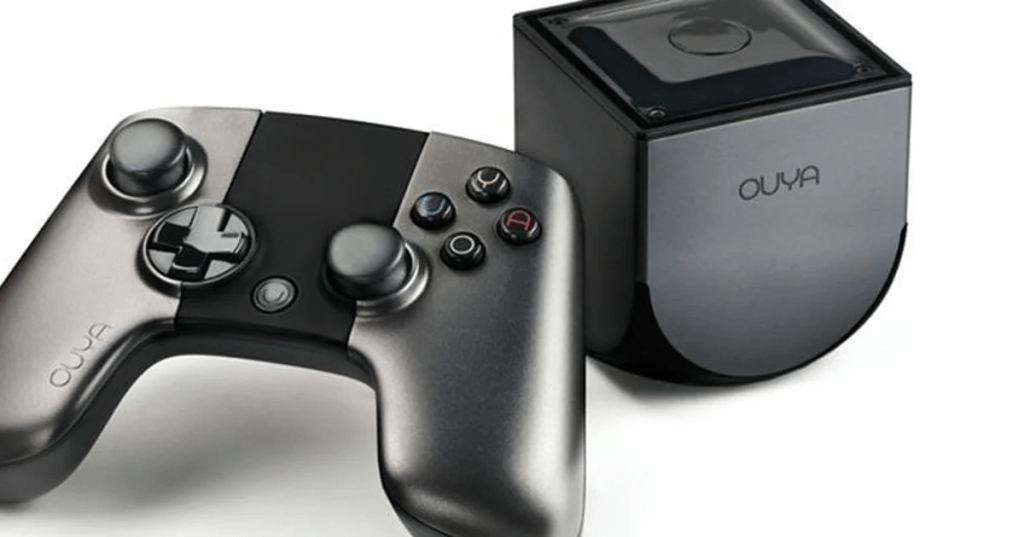 A close-up view of an OUYA gaming console and its accompanying controller, featuring a sleek black design with joystick and button controls.